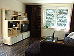 Wohnzimmer mit Fernseher, Radio und gemütlicher Eckcouch.